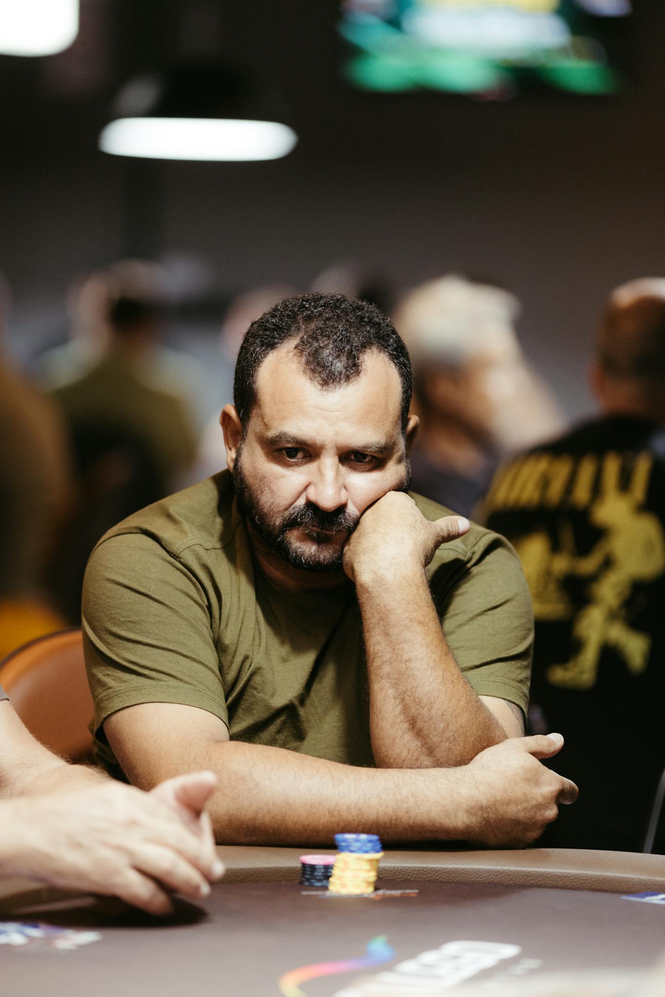 A man deeply focused while playing poker at a casino table with poker chips.