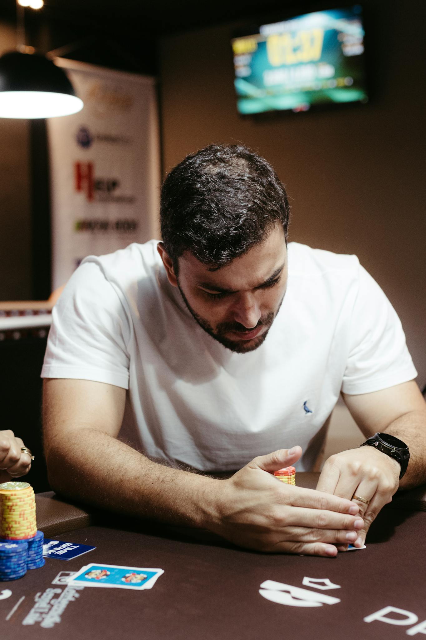 Adult male intensely strategizing in a poker game with cards and chips on the table.