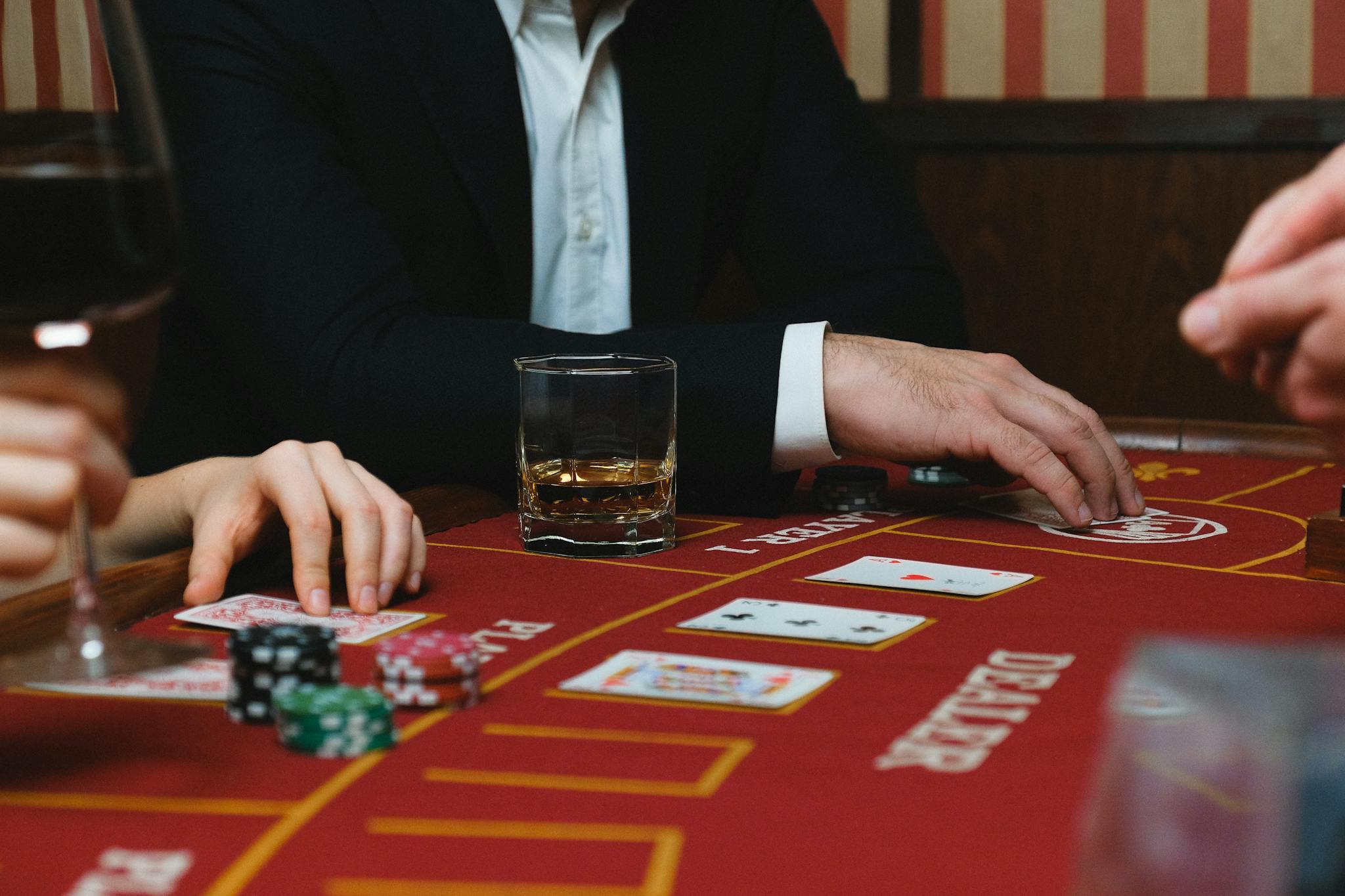 Close-up of a poker game with cards, chips, and players inside a casino setting.