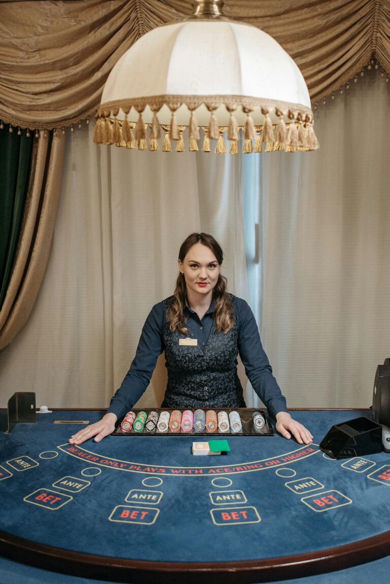 Female casino dealer standing behind a poker table in an elegant gambling hall.