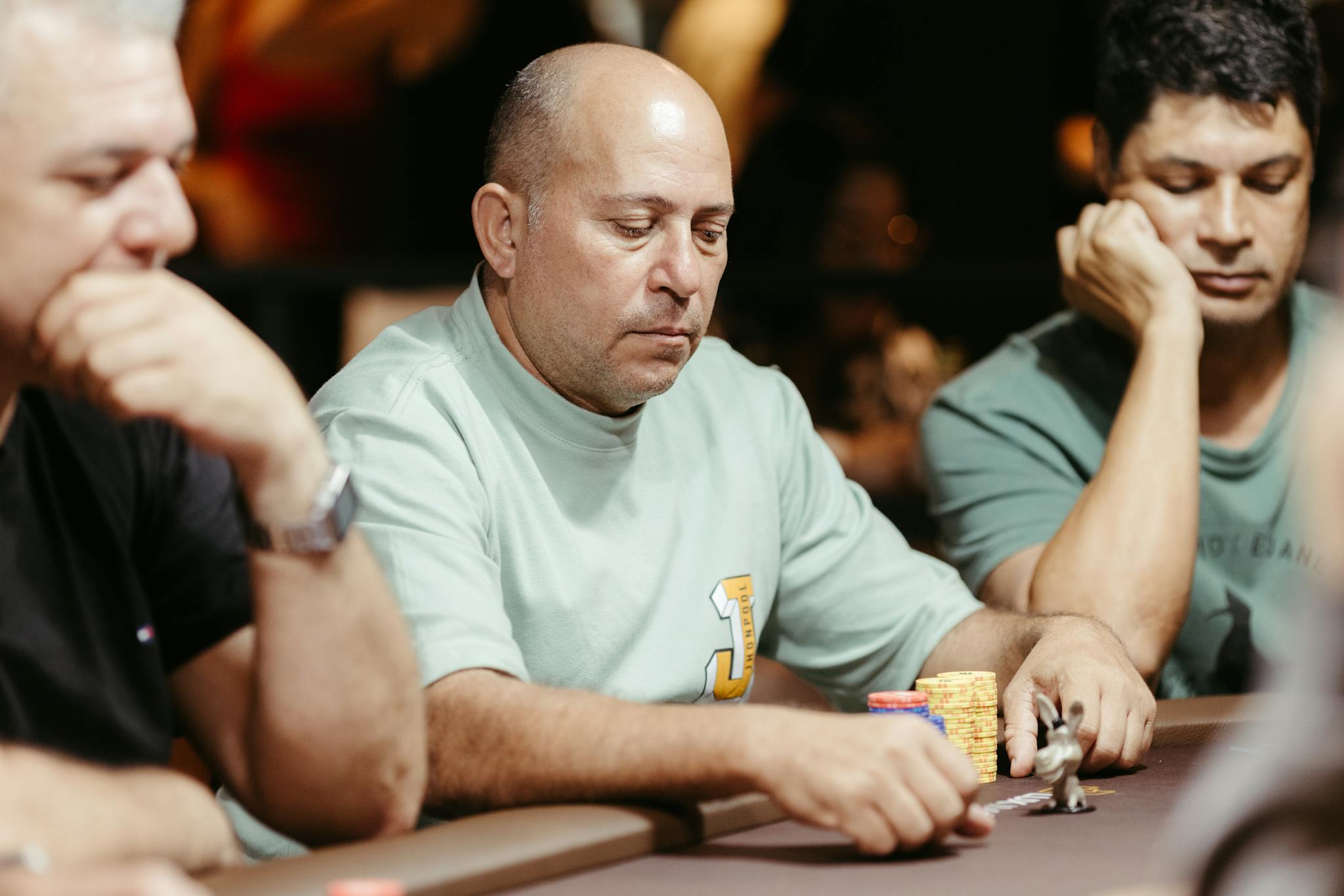 Group of adult men focused on a poker game at a casino table.
