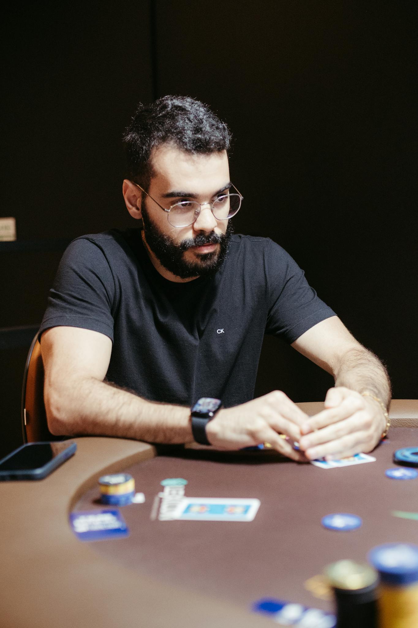 Poker player strategizing at a casino table, holding cards in a tense game setting.