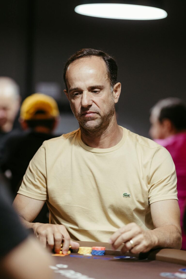 Serious poker player sitting at casino table focusing on his cards and poker chips.